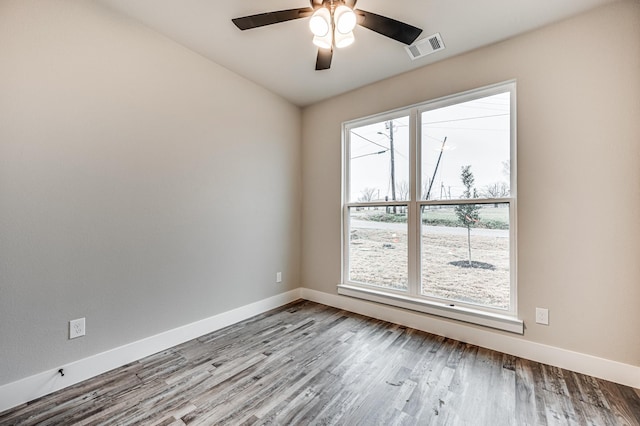 spare room with light wood finished floors, baseboards, visible vents, and ceiling fan