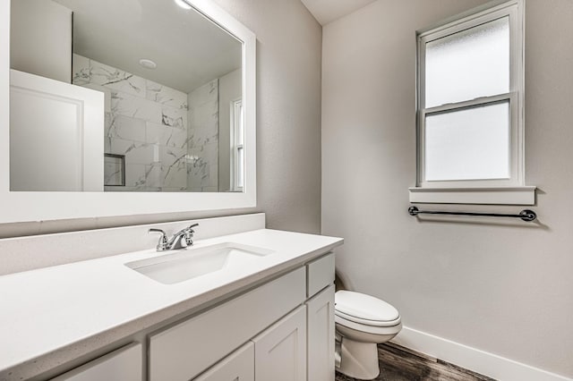 bathroom featuring toilet, wood finished floors, vanity, baseboards, and a marble finish shower