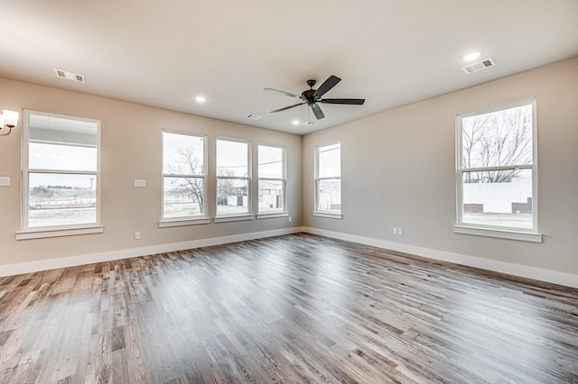 unfurnished room featuring visible vents, baseboards, and wood finished floors