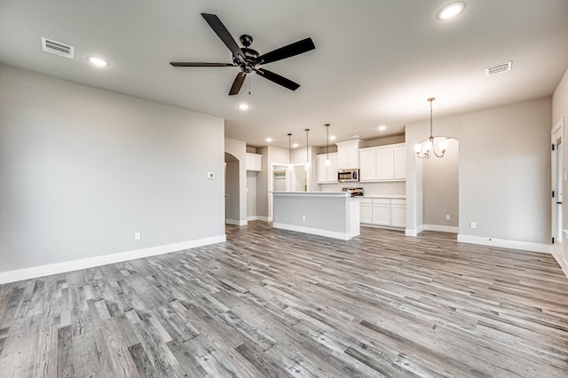 unfurnished living room with light wood-style floors, arched walkways, visible vents, and ceiling fan with notable chandelier