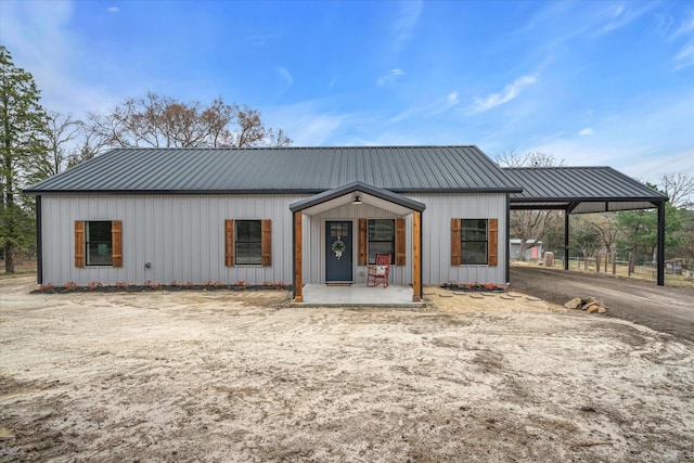 view of front of property featuring metal roof, an attached carport, board and batten siding, and a porch