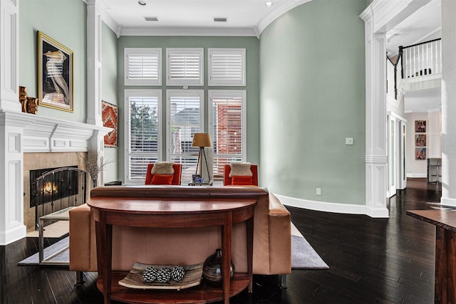 dining room with ornate columns, ornamental molding, dark wood-type flooring, and a fireplace