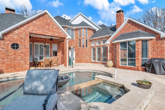 rear view of property with a patio and a pool with hot tub