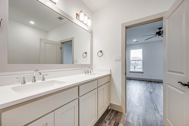 bathroom with double vanity, wood finished floors, a sink, and visible vents