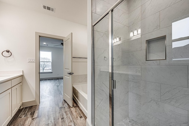 full bathroom with visible vents, a shower stall, vanity, wood finished floors, and a bath