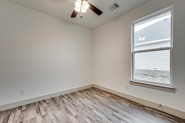 spare room with light wood finished floors, baseboards, visible vents, and ceiling fan