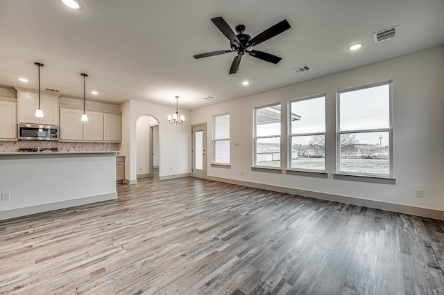 unfurnished living room with recessed lighting, visible vents, light wood-style flooring, and ceiling fan with notable chandelier