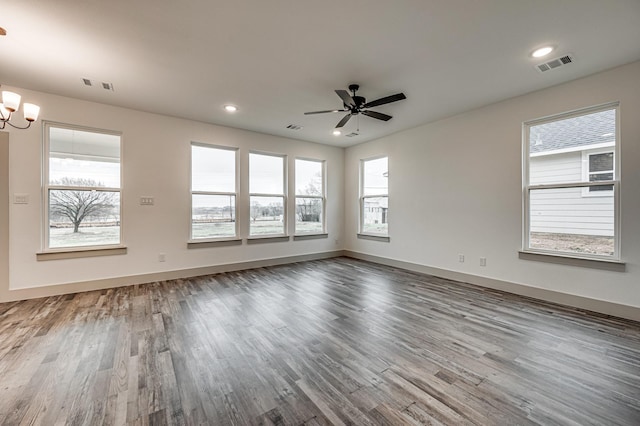 empty room featuring a wealth of natural light, visible vents, and wood finished floors