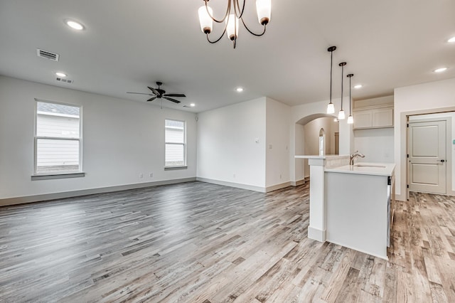 kitchen featuring an island with sink, open floor plan, light countertops, and decorative light fixtures