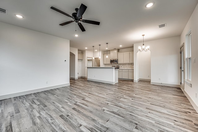 unfurnished living room featuring recessed lighting, visible vents, light wood-style floors, baseboards, and ceiling fan with notable chandelier