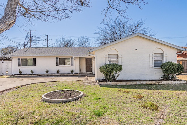 single story home featuring roof with shingles, fence, a front lawn, and brick siding