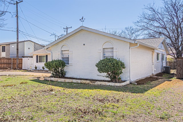 view of home's exterior with a lawn, fence, cooling unit, and brick siding