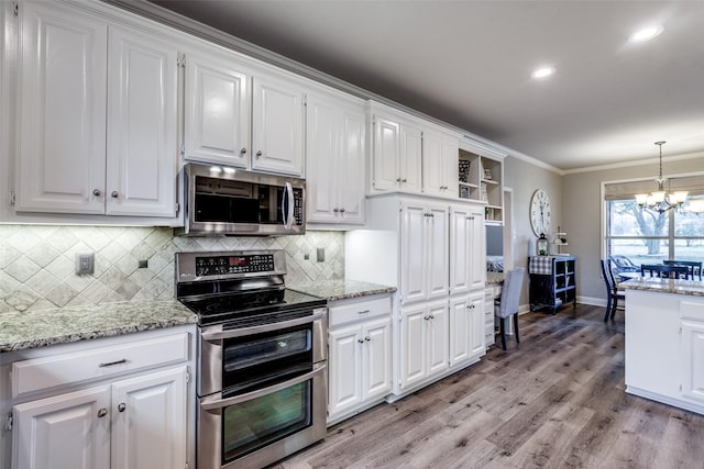 kitchen featuring stainless steel appliances, white cabinetry, and decorative light fixtures