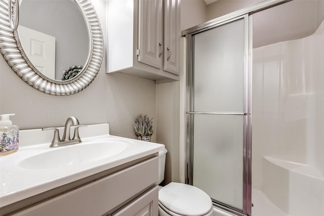 bathroom with vanity, toilet, and a shower with door