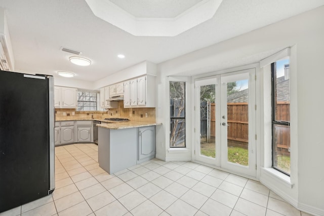 kitchen with stainless steel appliances, white cabinets, light tile patterned floors, and backsplash