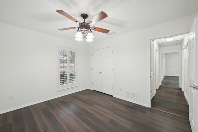 unfurnished bedroom with ceiling fan, dark hardwood / wood-style floors, a closet, and a textured ceiling