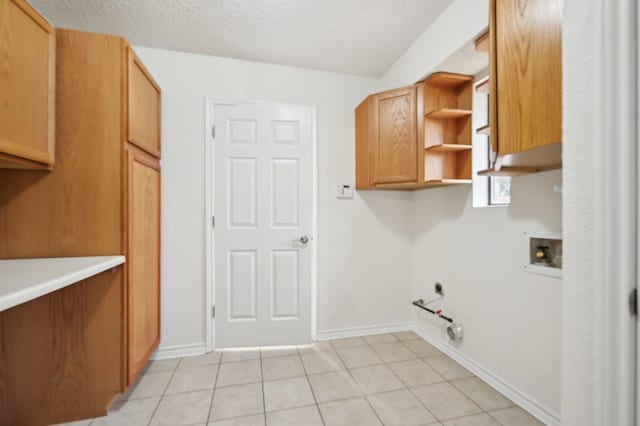 clothes washing area with gas dryer hookup, cabinets, a textured ceiling, light tile patterned floors, and hookup for a washing machine