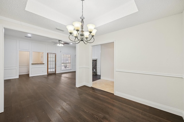 unfurnished dining area with dark hardwood / wood-style flooring, ceiling fan with notable chandelier, a raised ceiling, and a textured ceiling