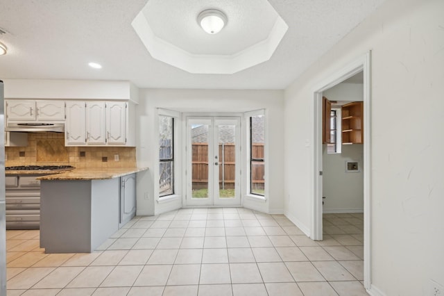 kitchen with light stone counters, white cabinetry, tasteful backsplash, a textured ceiling, and light tile patterned floors