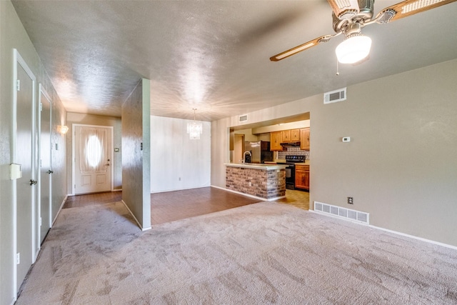 interior space featuring ceiling fan, light carpet, and a textured ceiling