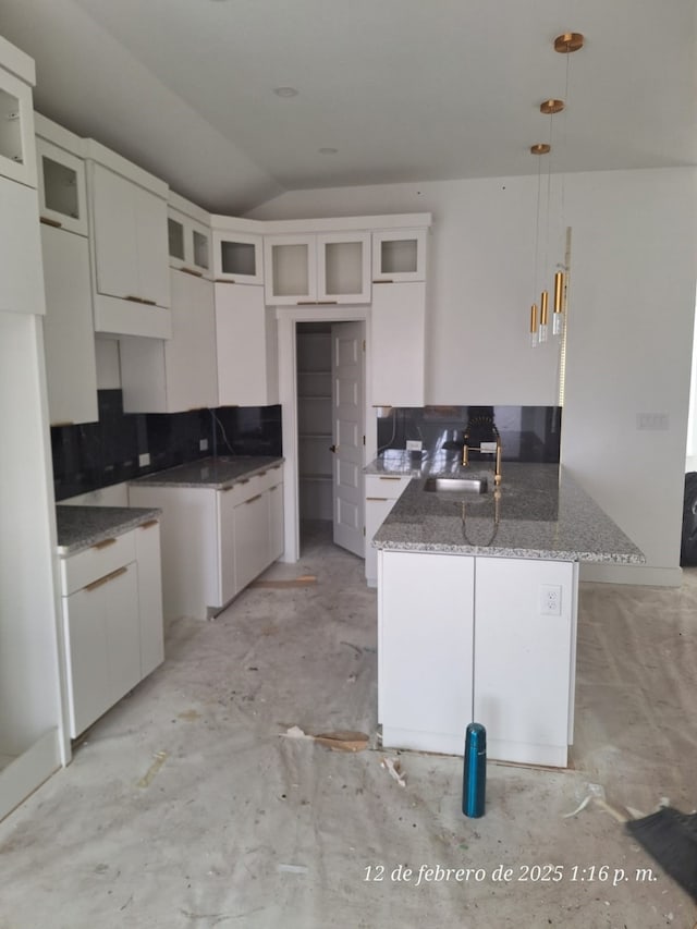 kitchen with white cabinetry, hanging light fixtures, lofted ceiling, and sink