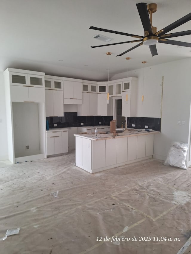 kitchen with hanging light fixtures, sink, white cabinets, and ceiling fan