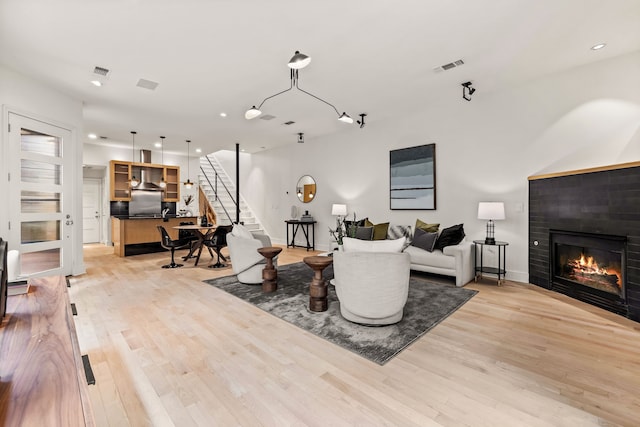 living room with a tile fireplace and light hardwood / wood-style flooring