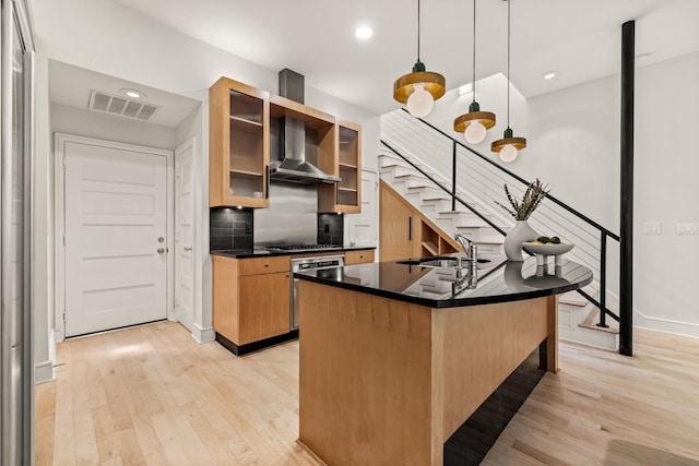 kitchen with sink, decorative backsplash, hanging light fixtures, wall oven, and light wood-type flooring