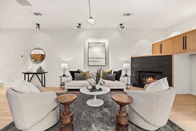 living room featuring a tiled fireplace and light hardwood / wood-style flooring