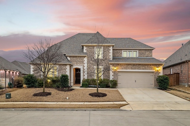 view of front of property with driveway, a garage, a shingled roof, fence, and brick siding