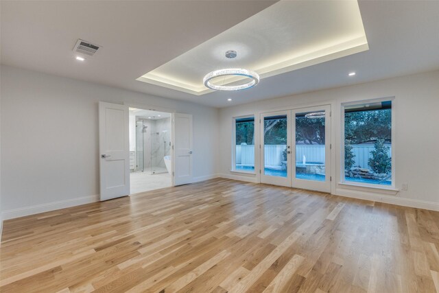 bedroom with ensuite bath, hardwood / wood-style floors, a tray ceiling, access to outside, and french doors