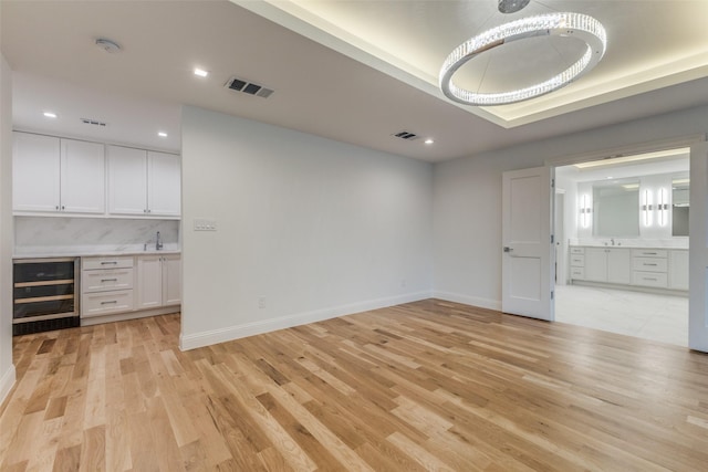 empty room featuring french doors, a tray ceiling, and light hardwood / wood-style floors