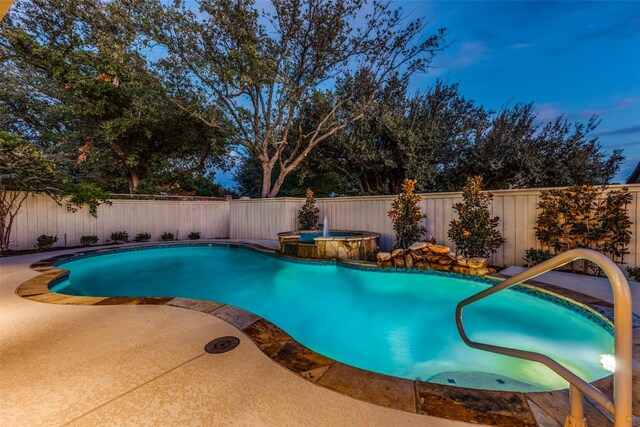 pool at dusk with a patio area and an in ground hot tub