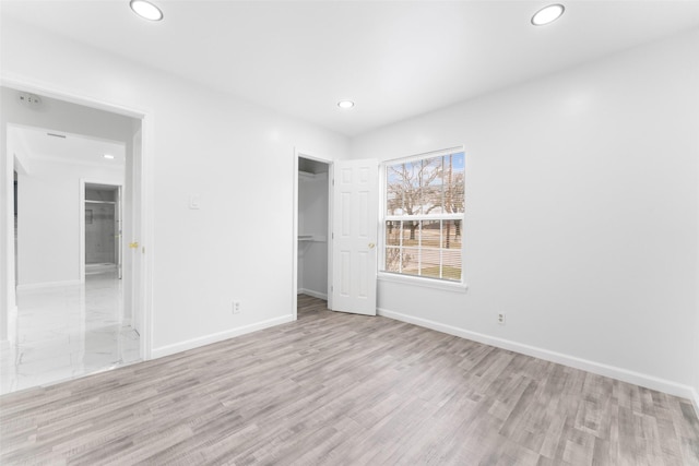 unfurnished bedroom with a closet, recessed lighting, baseboards, and wood finished floors