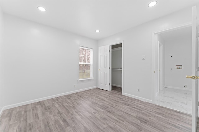 unfurnished bedroom featuring a walk in closet, light hardwood / wood-style floors, and a closet