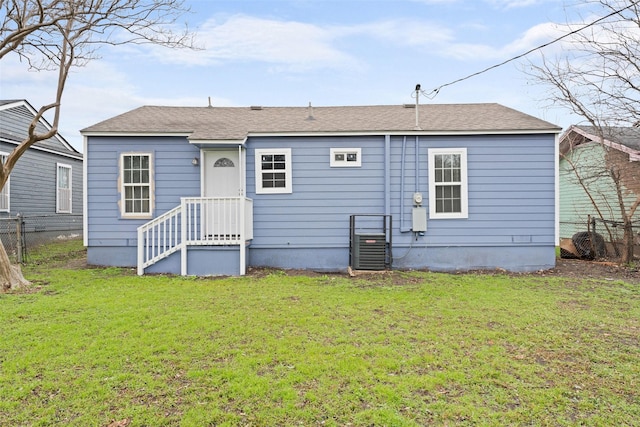 rear view of house featuring central air condition unit, a lawn, and fence