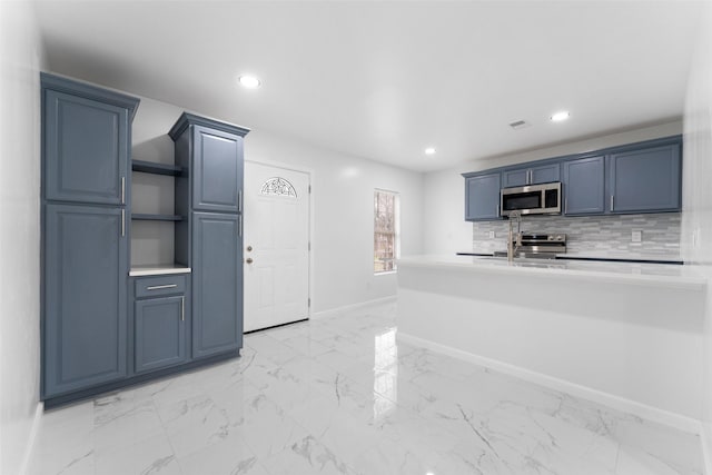 kitchen featuring baseboards, light countertops, decorative backsplash, marble finish floor, and stainless steel appliances