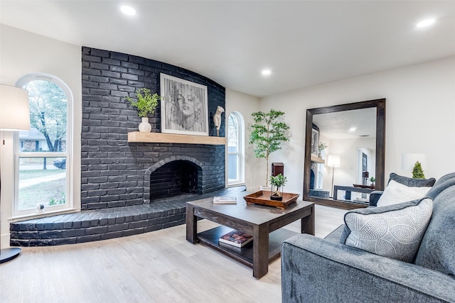 living room with wood-type flooring and a brick fireplace