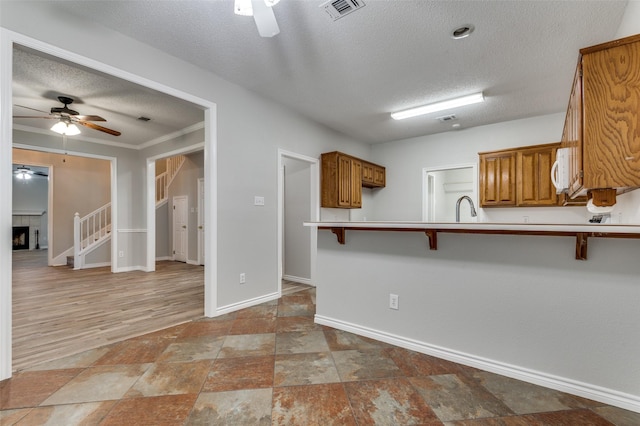 1230 Wooded Trl, Hurst, TX 76053 - kitchen featuring a ceiling fan, a textured ceiling, a kitchen bar, a sink, and white microwave