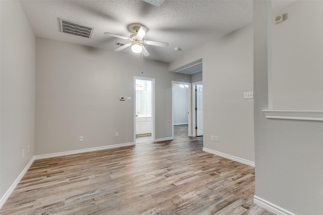 1230 Wooded Trl, Hurst, TX 76053 - empty room with a ceiling fan, light wood-style floors, baseboards, a textured ceiling, and attic access