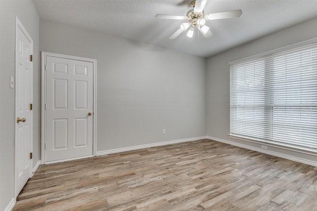 1230 Wooded Trl, Hurst, TX 76053 - empty room with light wood-type flooring, ceiling fan, baseboards, and a textured ceiling