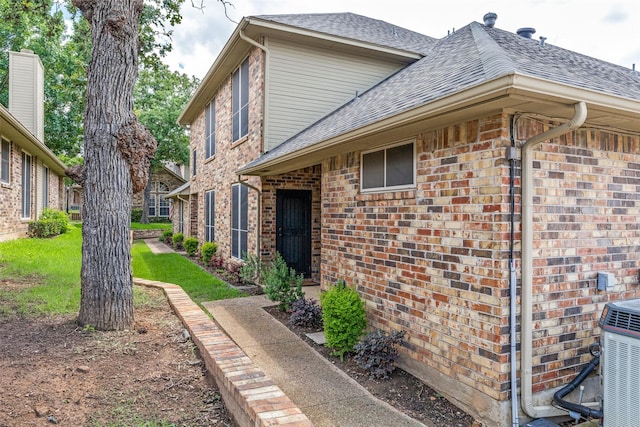 1230 Wooded Trl, Hurst, TX 76053 - view of side of home with roof with shingles, brick siding, central air condition unit, and a lawn