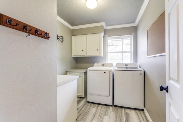 washroom featuring crown molding, cabinets, separate washer and dryer, a textured ceiling, and light wood-type flooring