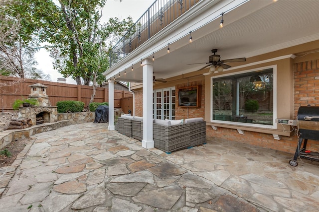 view of patio with an outdoor living space with a fireplace and ceiling fan