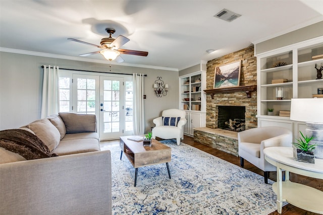 living room featuring crown molding, a stone fireplace, wood-type flooring, and french doors