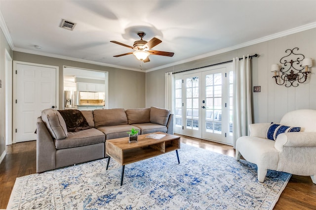 living room with dark wood-type flooring, ornamental molding, and french doors