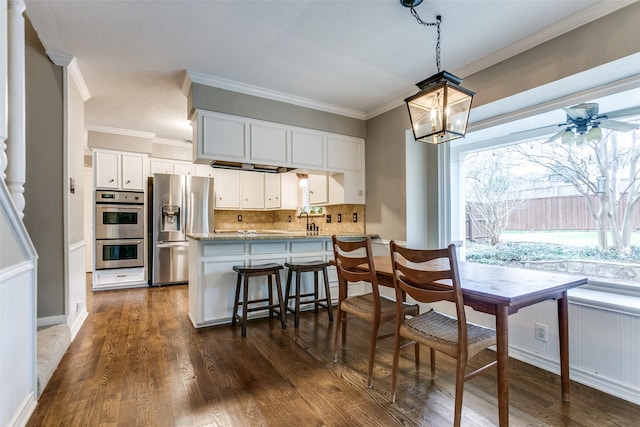 kitchen featuring stainless steel appliances, white cabinetry, crown molding, and kitchen peninsula