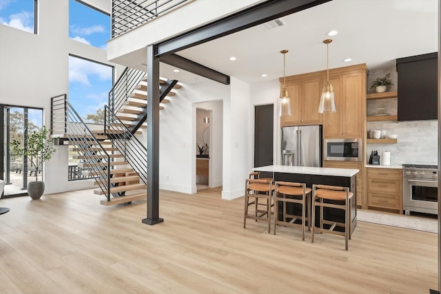 kitchen featuring hanging light fixtures, light wood-type flooring, high quality appliances, and a kitchen bar