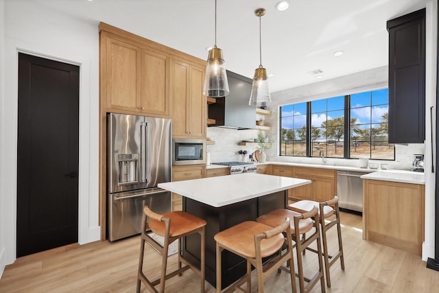 kitchen featuring tasteful backsplash, light wood-type flooring, a kitchen island, island exhaust hood, and stainless steel appliances