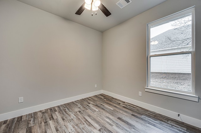 spare room featuring ceiling fan, wood-type flooring, and a healthy amount of sunlight